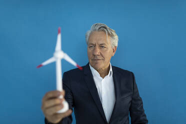 Senior businessman holding wind turbine model - GUSF02594