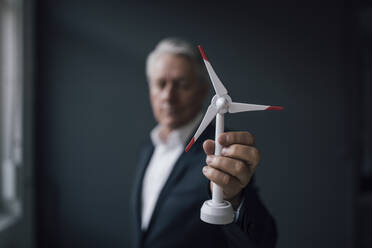 Senior businessman holding wind turbine model - GUSF02602