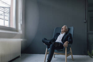 Älterer Geschäftsmann sitzt mit geschlossenen Augen im Sessel - GUSF02615