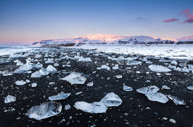 Blick auf Eisberge am schwarzen Strand gegen den Himmel bei Sonnenuntergang, Jokulsarlon, Island - XCF00208