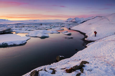 Tourist beim Fotografieren an der Lagune Jokulsarlon gegen den Himmel bei Sonnenuntergang, Island, lizenzfreies Stockfoto