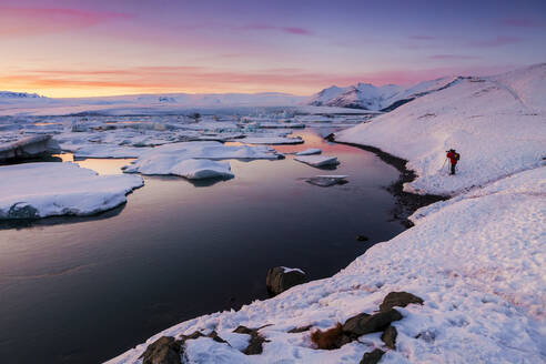 Tourist beim Fotografieren an der Lagune Jokulsarlon gegen den Himmel bei Sonnenuntergang, Island - XCF00212