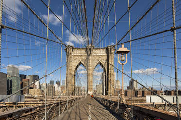 Diminishing perspective of Brooklyn Bridge against blue sky in New York City, USA - XCF00215