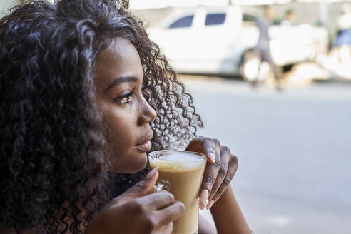 Porträt einer jungen afrikanischen Frau in einem Café, die aus dem Fenster schaut - VEGF00697