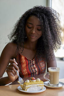 Porträt einer jungen Afrikanerin, die ein Stück Kuchen isst und einen Kaffee trinkt - VEGF00700