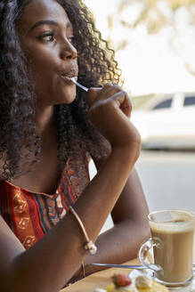 Porträt einer jungen Afrikanerin, die ein Stück Kuchen isst und einen Kaffee trinkt - VEGF00702