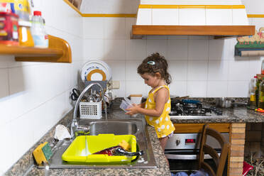 Kleines Mädchen wäscht in der Küche zu Hause Geschirr - GEMF03135