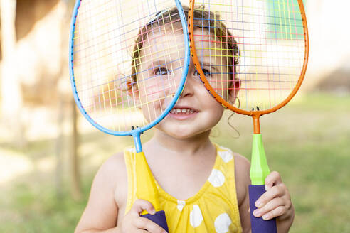 Kleines Mädchen spielt mit bunten Badmintonschlägern im Freien im Sommer - GEMF03147