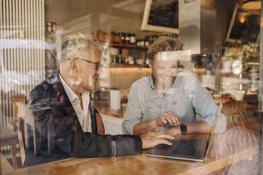 Two smiling businessmen with laptop meeting in a cafe - GUSF02619