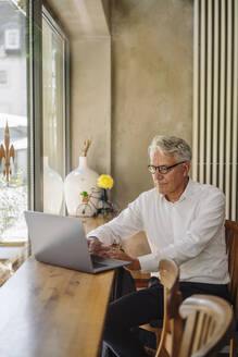 Älterer Geschäftsmann benutzt Laptop in einem Café - GUSF02621