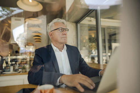 Älterer Geschäftsmann benutzt Laptop in einem Café - GUSF02634