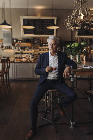 Porträt eines älteren Geschäftsmannes, der in einem Café Espresso trinkt, lizenzfreies Stockfoto