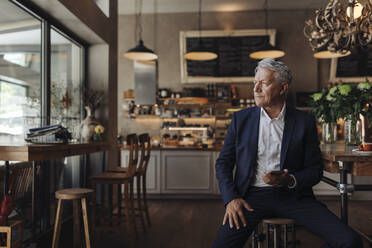 Senior businessman with cell phone in a cafe - GUSF02644