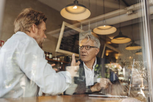 Two businessmen with laptop meeting in a cafe - GUSF02650