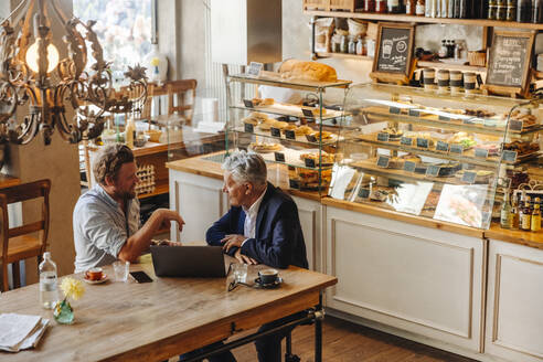 Zwei Geschäftsleute mit Laptop treffen sich in einem Cafe - GUSF02651