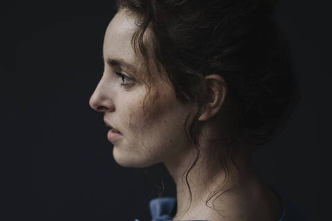 Profile of young woman against dark background stock photo