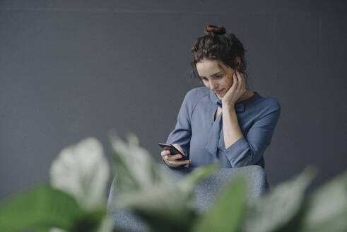 Porträt einer jungen Frau, die auf ein Mobiltelefon schaut - KNSF06551