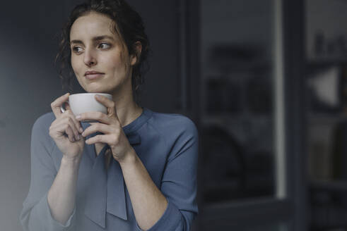 Porträt einer jungen Frau, die sich mit einer Tasse Kaffee entspannt - KNSF06552