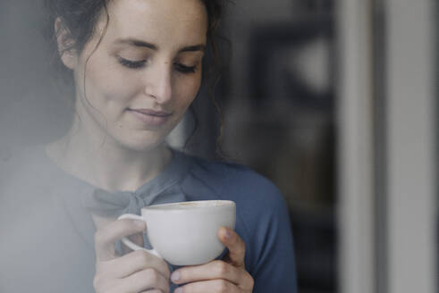 Porträt einer jungen Frau, die sich mit einer Tasse Kaffee entspannt - KNSF06553