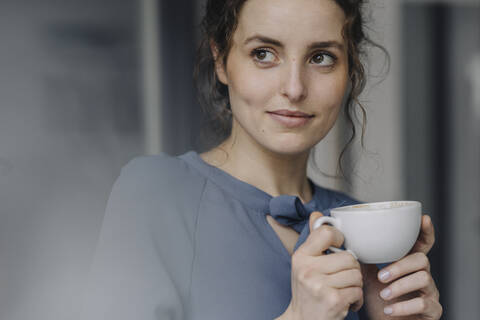 Porträt einer jungen Frau, die sich mit einer Tasse Kaffee entspannt, lizenzfreies Stockfoto