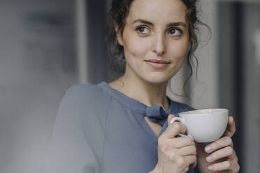 Porträt einer jungen Frau, die sich mit einer Tasse Kaffee entspannt - KNSF06554