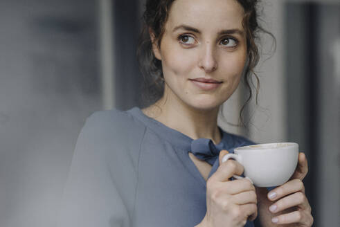 Portrait of young woman relaxing with cup of coffee - KNSF06554