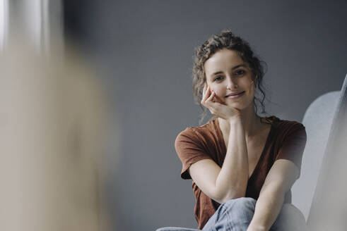 Porträt einer lächelnden jungen Frau, die sich zu Hause entspannt - KNSF06559