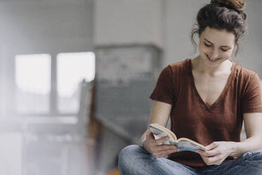 Lächelnde junge Frau liest ein Buch - KNSF06565