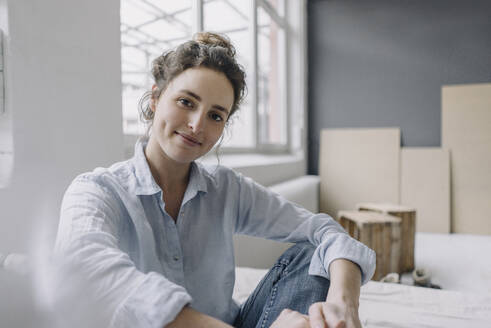 Portrait of smiling young woman relaxing at home - KNSF06571