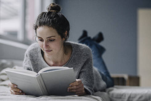 Portrait of young woman reading book at home - KNSF06584