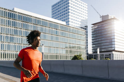 Junger Mann joggt in der Stadt und hört Musik, lizenzfreies Stockfoto