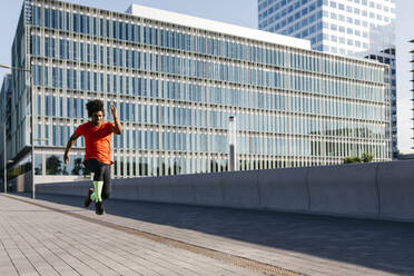Young man jumping in the city, listening to music - JRFF03710