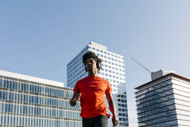 Junger Mann joggt in der Stadt und hört Musik - JRFF03716