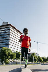 Young man jogging in the city, listening to music - JRFF03717