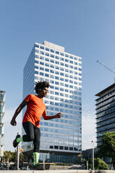Young man jogging in the city, listening to music - JRFF03719