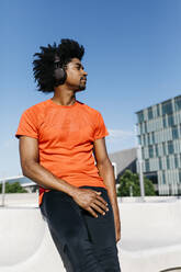 Young man jogging in the city, listening to music - JRFF03726