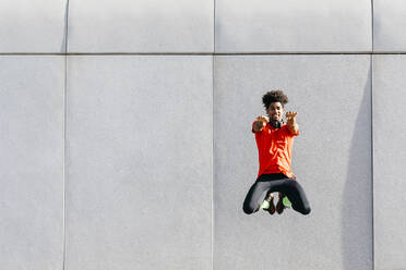 Young man doing jumps with a gray wall in the background - JRFF03739