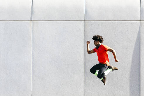 Young man doing jumps with a gray wall in the background - JRFF03740