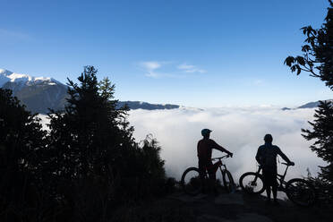 Mountainbiker blicken beim Radfahren in der Gosainkund-Region, Langtang-Region, Nepal, Asien, über ein Tal mit einer Wolkeninversion im Himalaya - RHPLF09849