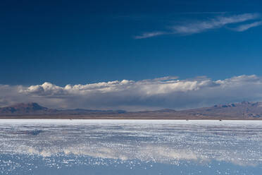 Die Schönheit der Salzebenen, in denen sich die Wolken und Berge nach Regenfällen spiegeln, drei 4WD-Fahrzeuge in der Ferne, Uyuni, Bolivien, Südamerika - RHPLF09865