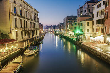 Abendlicher Kanalblick auf niedrige traditionelle Gebäude und hölzerne Kai-Pfähle mit vertäuten Booten, Venedig, UNESCO-Weltkulturerbe, Venetien, Italien, Europa - RHPLF10043