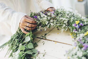 Woman preparing flower wreath - JOHF00322