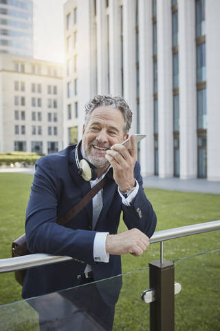 Älterer Geschäftsmann benutzt Smartphone in der Stadt, lizenzfreies Stockfoto