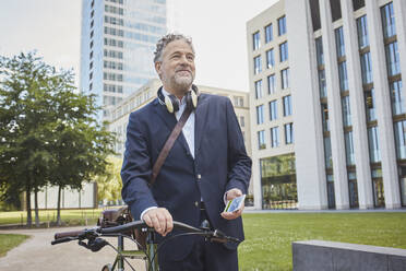 Älterer Geschäftsmann mit Fahrrad in der Stadt - RORF01847