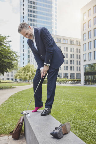 Älterer Geschäftsmann beim Golfspielen in der Stadt, lizenzfreies Stockfoto