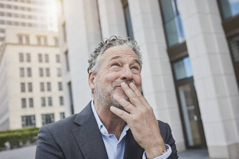 Portrait of happy businessman in the city looking up - RORF01899