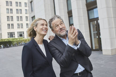 Happy businessman and businesswoman in the city looking up - RORF01906