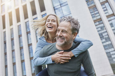 Happy mature man carrying woman piggyback in the city - RORF01913