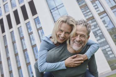 Happy mature man carrying woman piggyback in the city - RORF01914