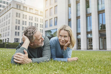 Relaxed mature couple lying on lawn in the city - RORF01924